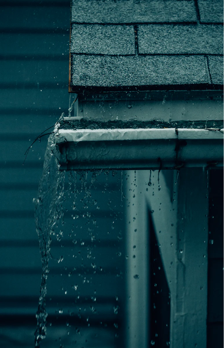 Water pouring off a roof edge during a storm