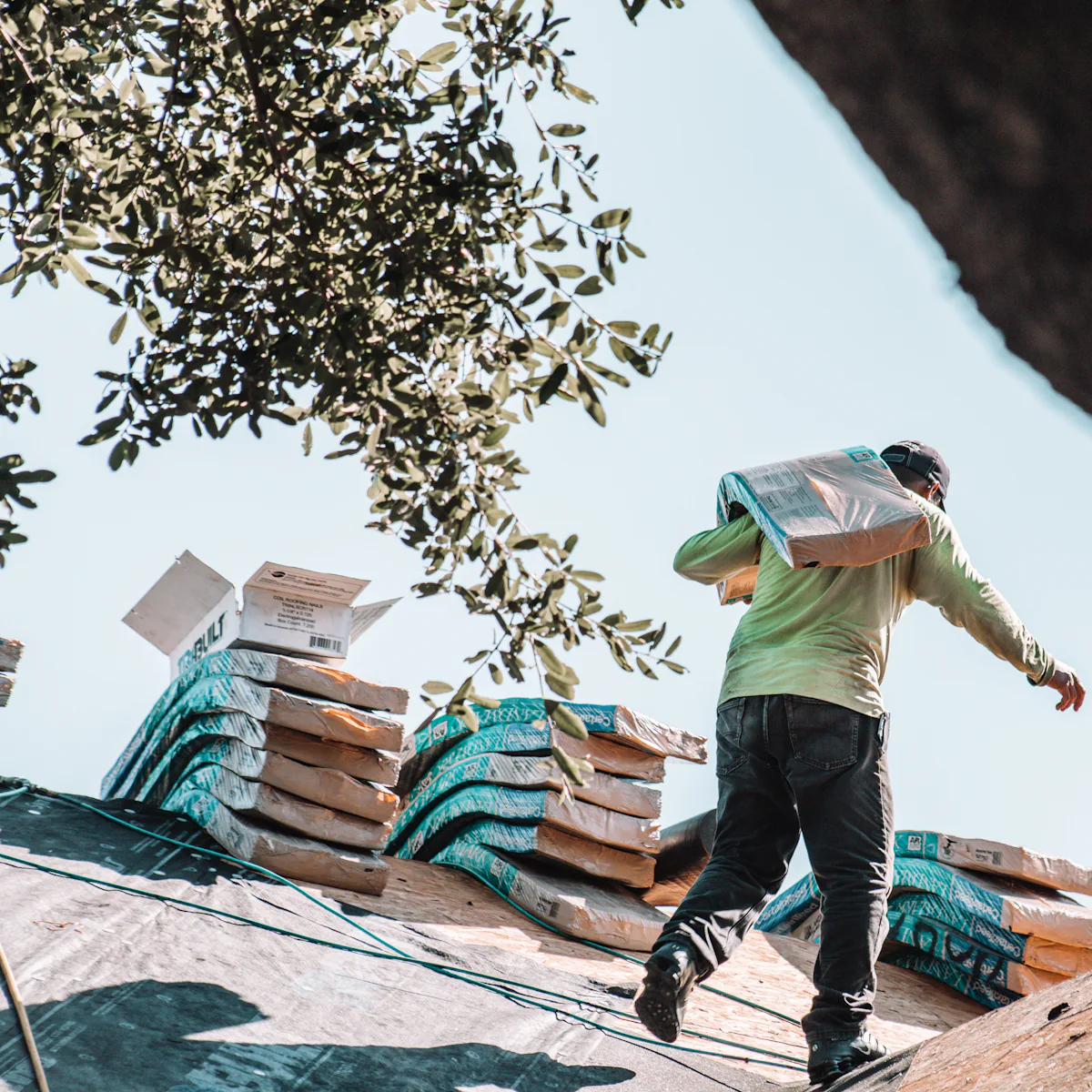 Roofer carrying bundles of new shingles